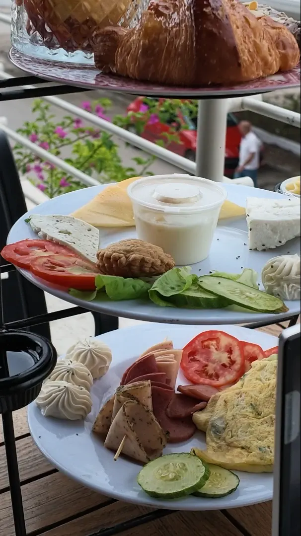 Les étages d'un présentoir de brunch, fromages, omelette et charcuterie, devant les bougainvilliers en fleurs.